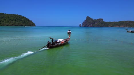 Koh-Phi-Phi-Bay,-colorful-traditional-longtail-boats-are-floating-on-calm-turquoise-water