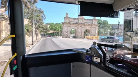 Vista-Desde-Un-Autobús-Público-Que-Recorre-La-Valeta,-Malta,-Comenzando-En-Portes-Des-Bombes,-Una-Puerta-Arqueada-Ornamental-Originalmente-Llamada-Porta-Dei-Cannoni,-Un-Hito-Histórico