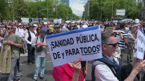 In-downtown-Madrid,-a-female-protester-holds-a-placard-reading-'Healthcare-for-everyone'-during-a-march-to-defend-public-healthcare