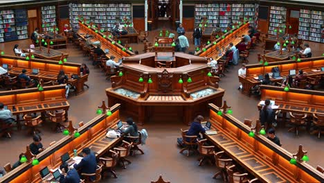 Gran-Interior-De-La-Sala-De-Lectura-La-Trobe-En-La-Biblioteca-Estatal-Victoria-En-La-Ciudad-De-Melbourne-Con-Hileras-De-Escritorios-De-Madera,-Lámparas-De-Lectura-Verdes-Y-Amplias-Estanterías,-Un-Ambiente-De-Estudio-Sereno