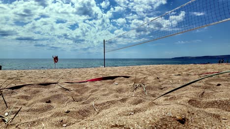 A-volleyball-net-on-a-sandy-beach-in-Crimea,-with-a-blue-sky-and-white-clouds