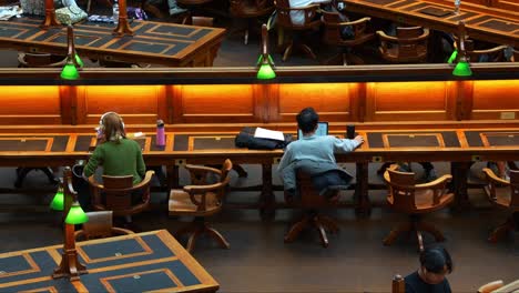 People-sitting-in-front-of-the-desk,-learning-in-the-grand-La-Trobe-Reading-Room-at-the-State-Library-Victoria,-in-Melbourne's-central-business-district,-concept-shot-of-Australian-students-HECS-debt