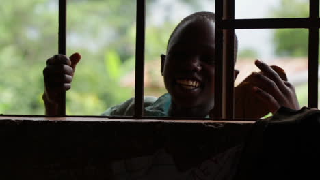 Niños-Negros-Africanos-Sonriendo-Frente-A-La-Cámara-Desde-Una-Ventana-Con-Barandillas-De-Hierro