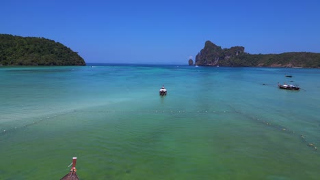 Koh-Phi-Phi-Bay,-colorful-traditional-longtail-boats-are-floating-on-calm-turquoise-water