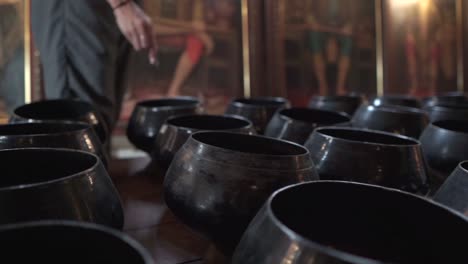 Girl-placing-coins-in-bowls-at-a-Buddhist-temple-in-Thailand