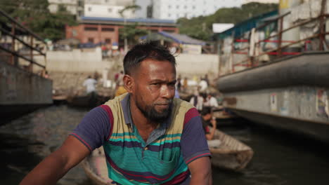 A-water-taxi-operator-paddles-through-a-busy-docking-area-on-the-Burangani-River-in-Dhaka,-Bangladesh