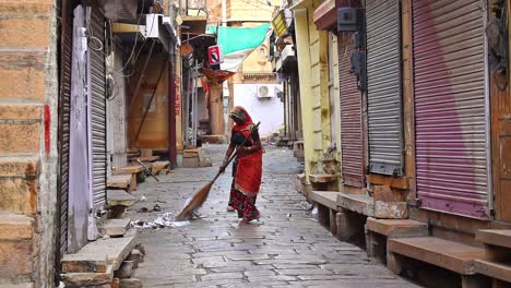 Street-cleaning-female-municipal-worker-in-uniform-sweeps-the-market-street-with-a-broom-in-old-Jais