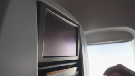 hand-tapping-on-aircraft-monitor-in-passenger-seat