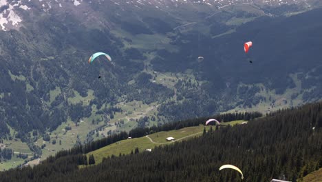Descending-Shot-of-Paragliders-Over-Green-Grindelwald-Valley