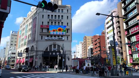 Busy-urban-intersection-with-pedestrians-and-cars-under-a-bright-blue-sky