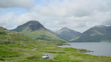 Cloud-shadows-racing-across-mountainous-countryside-with-lakeside-road-occupied-by-walkers-and-cars-near-mountains-Great-Gable-and-Scafell