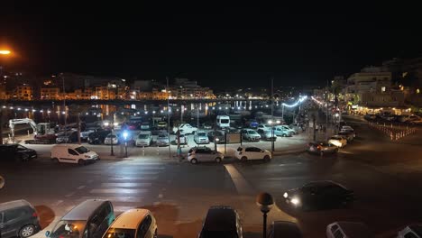 Beleuchtetes-Stadtzentrum-Von-Marsaskala-Und-Die-Bucht-Am-Abend-Mit-Einheimischen,-Die-Auf-Der-Promenade-In-Malta-Spazieren-Gehen