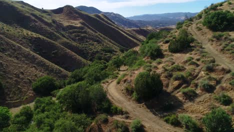 Toma-De-Drones-De-Tierras-De-Caza-En-Ranchos-Con-Caminos-De-Tierra-Volando-A-Través-Del-Cañón.