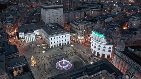 Piazza-De-Ferrari-at-night-with-pedestrians-and-traffic,-drone-establisher