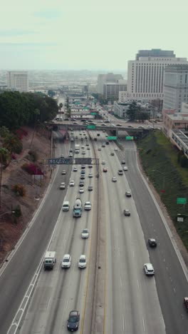 Los-Angeles,-Estados-Unidos,-Vista-Aérea-Vertical-Del-Tráfico-De-La-Autopista-Us-101-A-Lo-Largo-De-Los-Edificios-Del-Centro,-Autopista-De-Hollywood