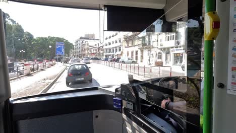 Observing-urban-exploration-and-daily-life-through-the-front-window-of-a-public-bus-traveling-along-the-streets-of-Valletta,-Malta