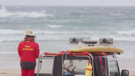 RNLI-lifeguard-on-beach-next-to-truck-keeps-watchful-eye-on-surfers-in-ocean