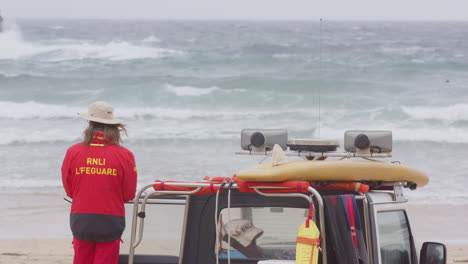 Rnli-Salvavidas-En-La-Playa-Junto-Al-Camión-Mantiene-Vigilante-A-Los-Surfistas-En-El-Océano