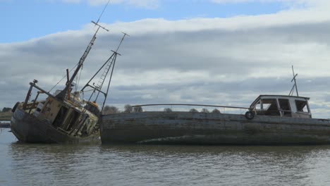 Abandoned-shipwrecks-in-receding-tide-with-thick-cloud-moving-across-the-frame-and-patches-of-sunlight-illuminating-the-scene