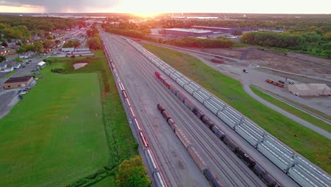 Aerial-view-of-a-railroad-yard-in-Illinois,-USA,-with-surrounding-industrial-area-and-greenery-during-sunset