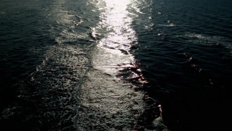 Dark-black-sea-background-with-mysterious-waves-rolling-across-the-water,-reflecting-light-and-creating-an-enigmatic-atmosphere