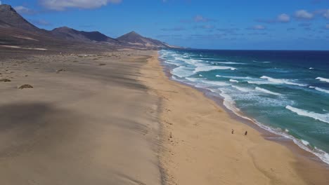 Flying-over-sand-beach-with-waving-ocean