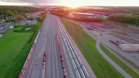 Sunset-aerial-view-of-a-railway-yard-at-sunset-in-Davenport,-Iowa---Silvis,-Illinois-showcasing-tracks,-trains,-and-surrounding-greenery