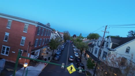 Aerial-flyover-main-street-of-american-town-with-parking-cars-at-dusk