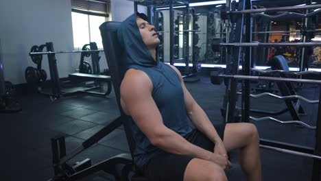 Tired-Caucasian-athlete-sportsman-takes-break-at-sport-gym-exhausted-sweaty-bodybuilder-hard-breathing-rest-after-weightlifting-exercise-workout-seated-on-bench-relax