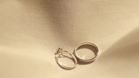 Dropping-a-pair-of-engagement-rings-on-a-soft-cottony-cloth-as-it-bounces-and-slowly-settles-in-the-middles-of-the-fabric