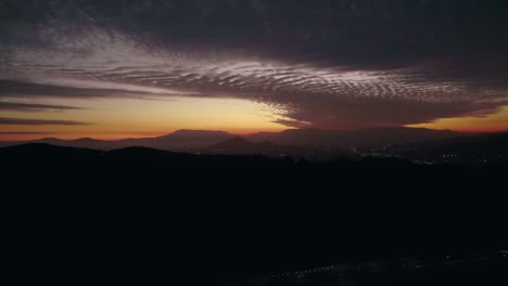 Aerial-tracking-shot-of-silhouette-island-hills,-dramatic-dusk-in-Santiago-de-Chile