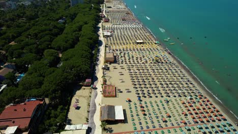 Large-beach-on-the-Durres-coast,-Albania,-with-green-pines,-white-sand,-turquoise-sea-water,-and-hotels-for-tourists