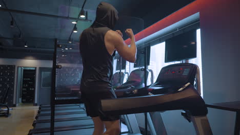 Sporty-Boxer-Man-in-30s-Trains-Shadowboxing-Technique-and-Boxing-Combinations-While-Walking-on-Treadmill-in-Empty-Modern-Gym-with-Changing-Ambient-Light
