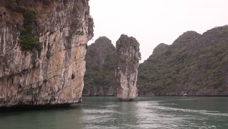 boat-floating-past-spire-rock-cliffs-in-Cat-Ba-and-Halong-Bay-in-Northern-Vietnam