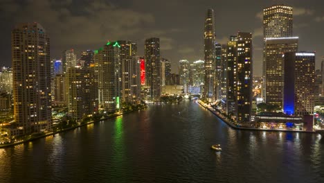 Aerial-night-hyper-lapse-of-brightly-lit-city-skyline-reflected-on-the-water