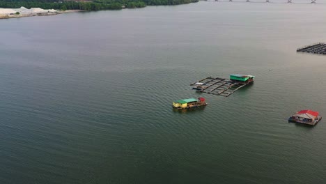 Aerial-view-showcasing-floating-fish-farms-highlights-traditional-aquaculture-practices,-including-the-breeding,-rearing,-cultivating,-and-harvesting-of-fish-and-shellfish-in-aquatic-environments