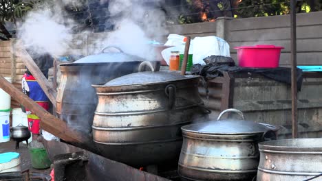 Afrikanische-Dame-Kocht-Essen-In-Gusseisernen-Töpfen-Auf-Einem-Markt