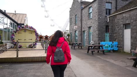 Rear-shot-of-woman-walking-to-Ferris-wheel-at-Mumbles-Pier,-Swansea-Bay,-Wales