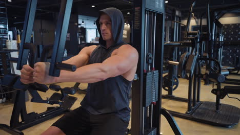 Un-Joven-Atlético-Y-Bien-Formado-Entrena-El-Pecho-Haciendo-Ejercicio-Con-Mosca-En-El-Pecho-En-El-Gimnasio