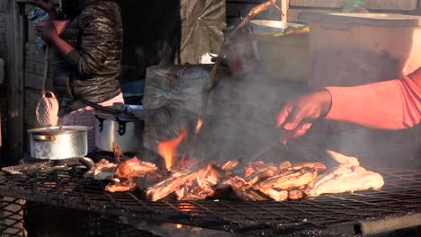 Afrikanische-Dame-Grillt-Fleisch-Auf-Heißen,-Feurigen-Kohlen-Auf-Einem-Kleinen-Lebensmittelmarkt