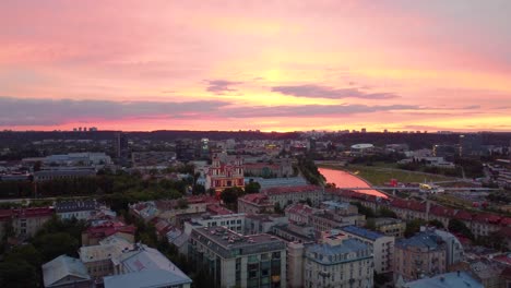 Aerial-view-captures-Vilnius-during-sunset,-painting-the-sky-with-hues-of-orange-and-pink