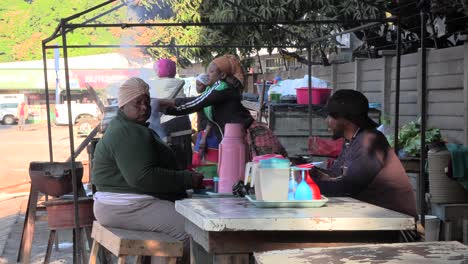 People-at-a-small-food-market-sit,-talk-and-continue-their-daily-lives