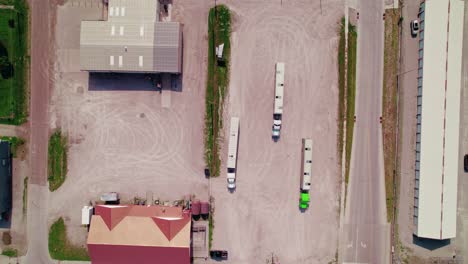Aerial-view-from-above-showing-three-livestock-trailers-with-trucks-parked-in-an-industrial-parking-lot