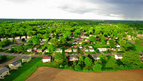 Aerial-view-of-Davenport,-Iowa,-capturing-a-residential-area-and-greenery-with-an-approaching-rainstorm-in-the-distance