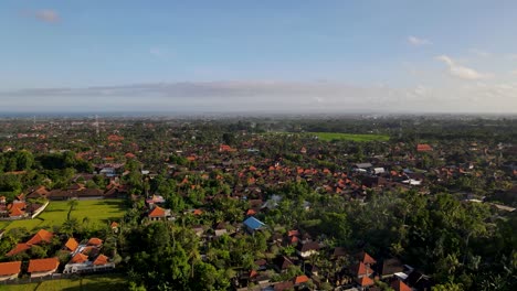 Aerial-view-of-Canggu-Village-in-Badung-Regency,-Bali,-Indonesia,-showcasing-the-picturesque-village-with-its-traditional-Balinese-architecture,-lush-greenery,-and-expansive-horizon