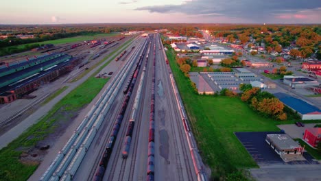 Beautiful-sunset-aerial-of-an-extensive-railroad-yard-and-surrounding-industrial-area-in-East-Moline,-Illinois,-during-sunset