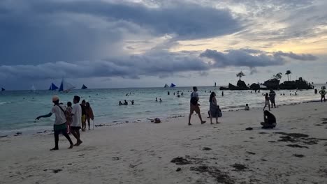 Toma-Manual-De-La-Playa-De-Boracay-En-Filipinas,-Panorámica-Hacia-La-Izquierda-Con-Gente-En-Una-Puesta-De-Sol-De-Junio-Con-Willy&#39;s-Rock