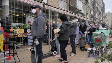 Multitud-De-Personas-Haciendo-Cola-Afuera-De-Una-Tienda-Con-Máscara-Durante-La-Epidemia-De-Covid,-Tel-Aviv