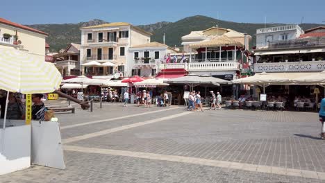 People-walking-at-noon-in-Parga-Greece's-town-square,-static-shot