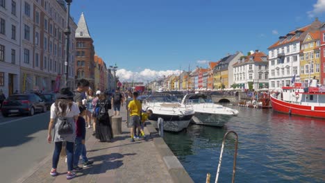 A-slow-motion-shot-following-tourists-walking-from-behind-next-to-a-lake-in-Copenhagen-during-the-summer-holidays